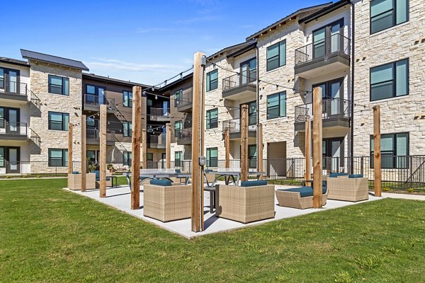 Outdoor recreational patio with seating and string lights at The Gin Mill Apartments, ideal for relaxation and entertainment