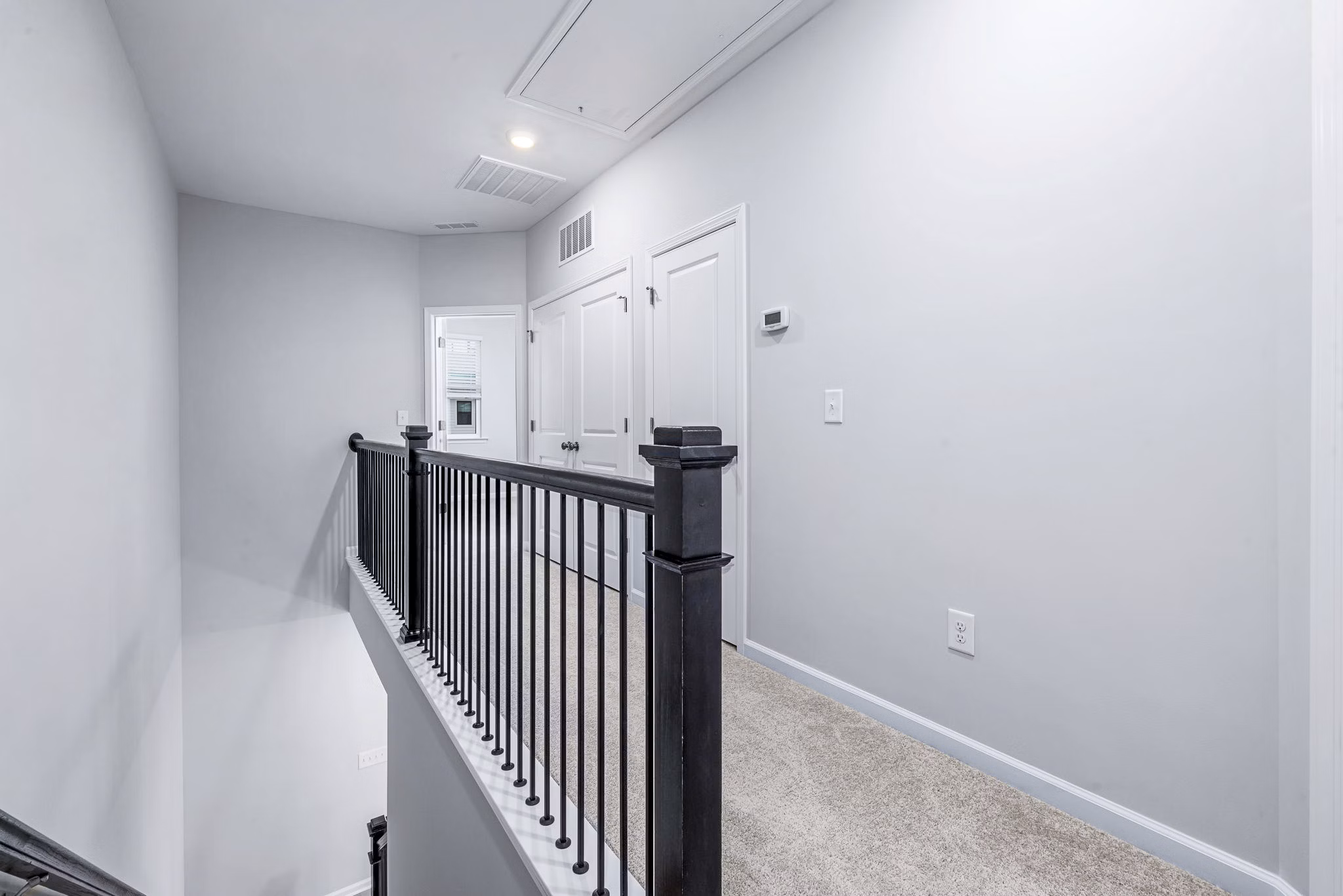 Hallway leading to bedrooms at Abode Kerr Ridge Apartments, showcasing sleek design and modern lighting