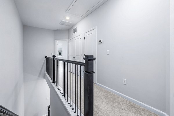 Hallway leading to bedrooms at Abode Kerr Ridge Apartments, showcasing sleek design and modern lighting