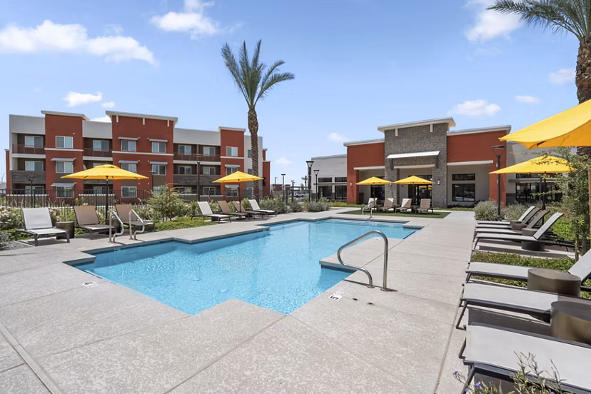 Resort-style pool at Prose at Ballpark Village Apartments with loungers and lush landscaping, offering a relaxing oasis for residents