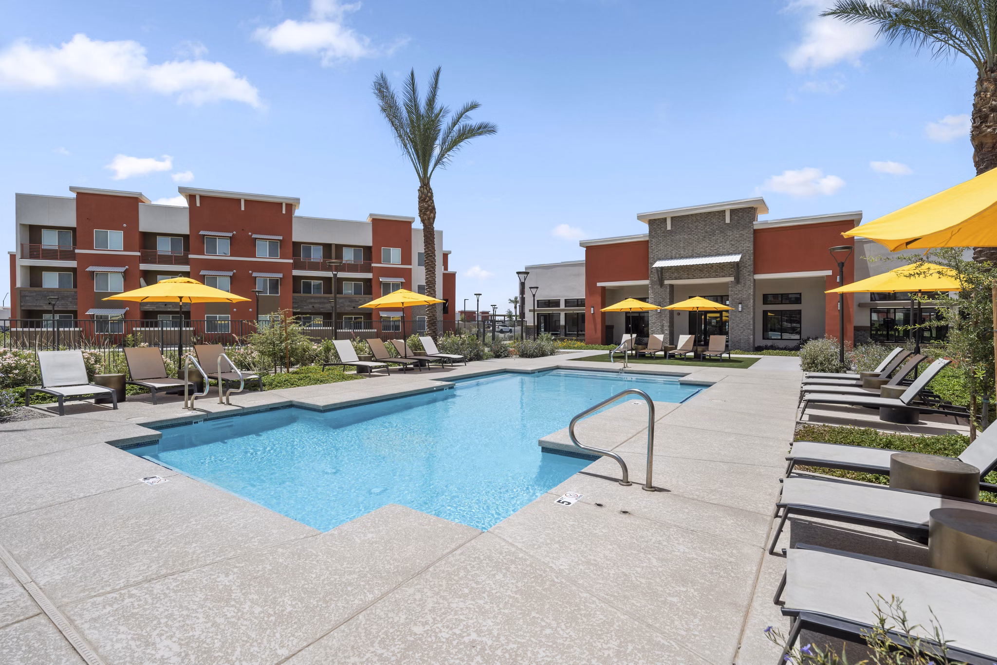 Resort-style pool at Prose at Ballpark Village Apartments with loungers and lush landscaping, offering a relaxing oasis for residents