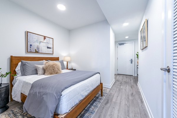 Modern bedroom featuring a cozy bed, decorative pillows, and stylish artwork in luxury apartments