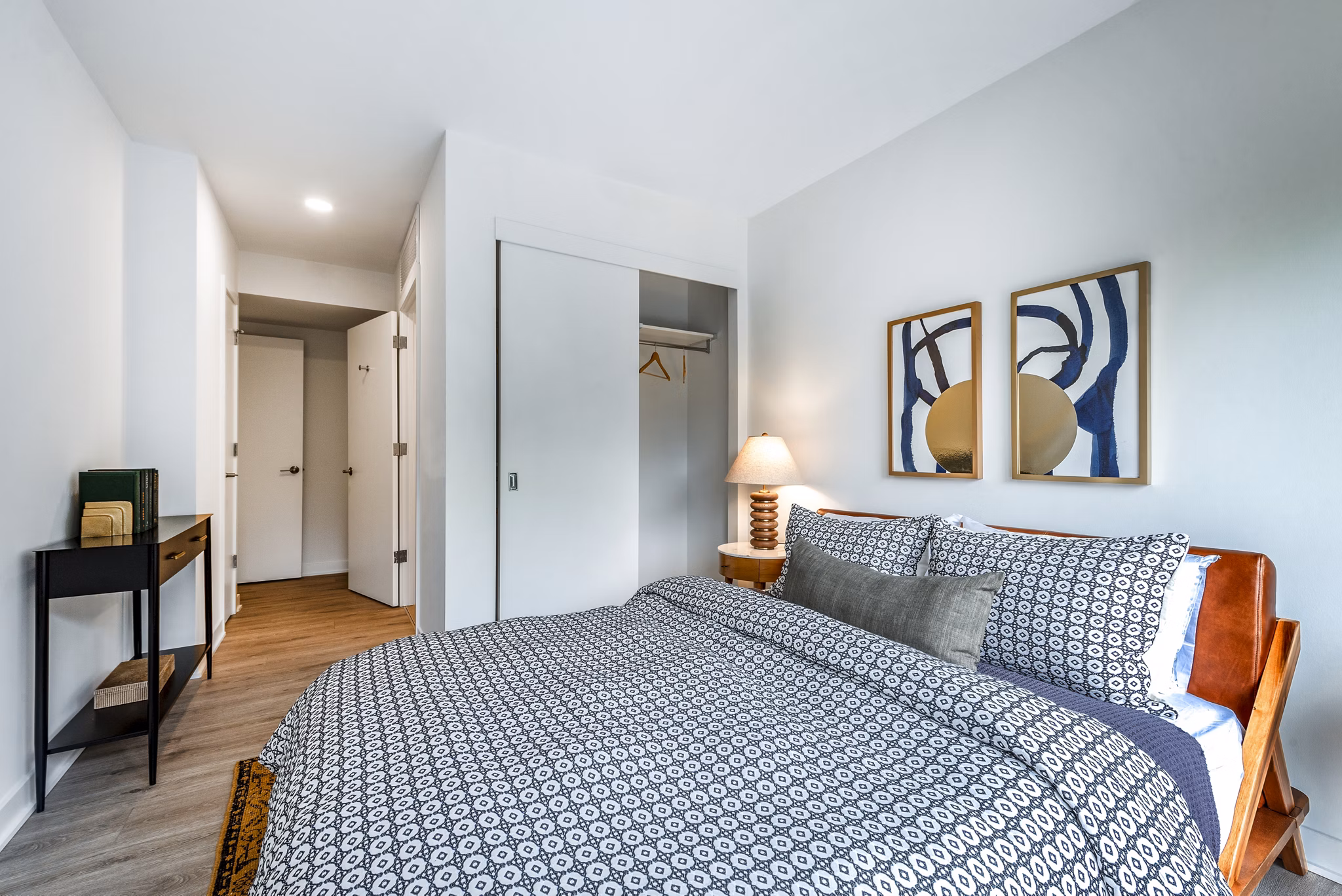Cozy bedroom featuring patterned bedding, abstract wall art, and a stylish lamp at luxury apartments