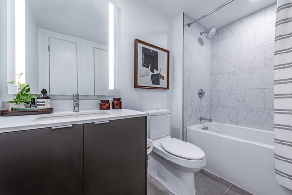 Modern bathroom featuring a stylish sink, mirror, and bathtub in luxury apartments