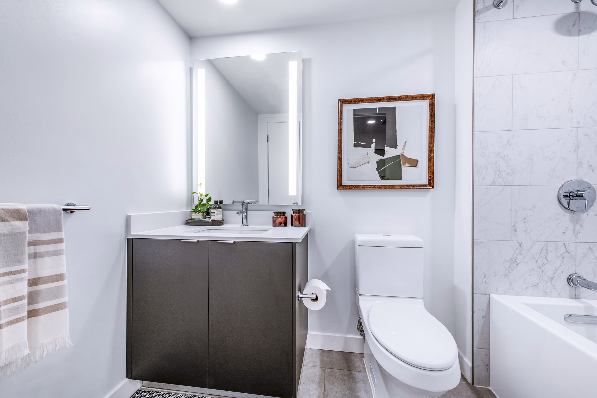 Modern bathroom featuring a stylish sink, mirror, bathtub, and towel rack in luxury apartments