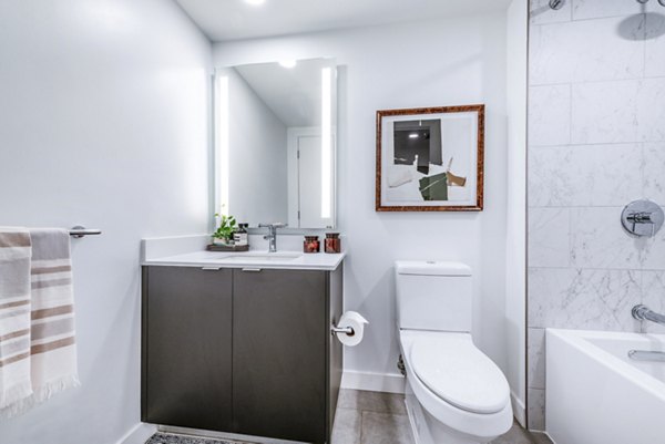 Modern bathroom featuring a stylish sink, mirror, bathtub, and towel rack in luxury apartments