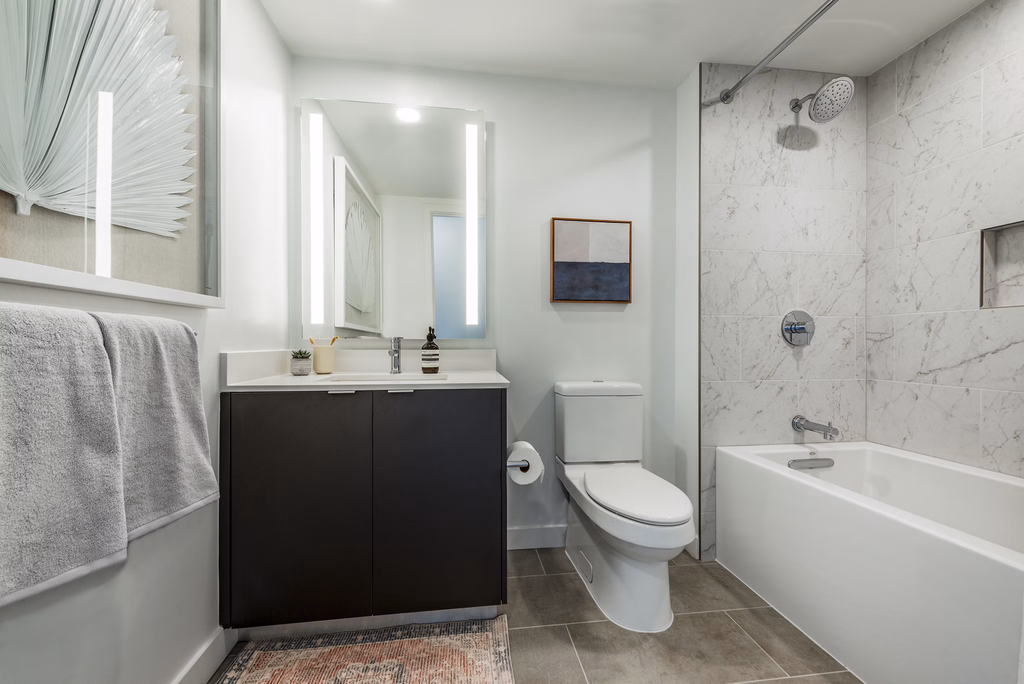 Modern bathroom featuring a sleek bathtub, shower, and vanity with mirror in luxury apartment