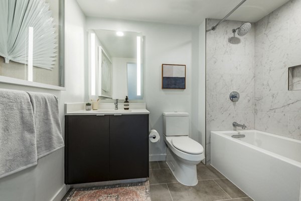 Modern bathroom featuring a sleek bathtub, shower, and vanity with mirror in luxury apartment