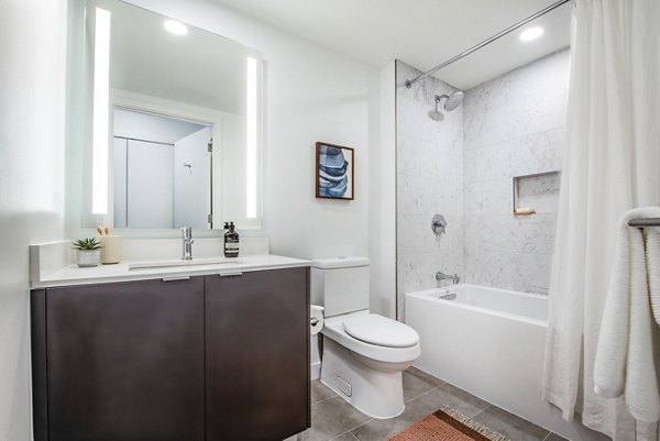 Modern bathroom with a sleek sink, mirror, and elegant tub in luxury apartments