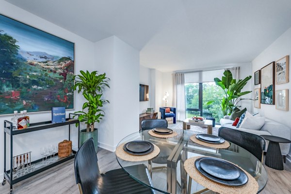 Modern living and dining area with glass table and black chairs in luxury apartment
