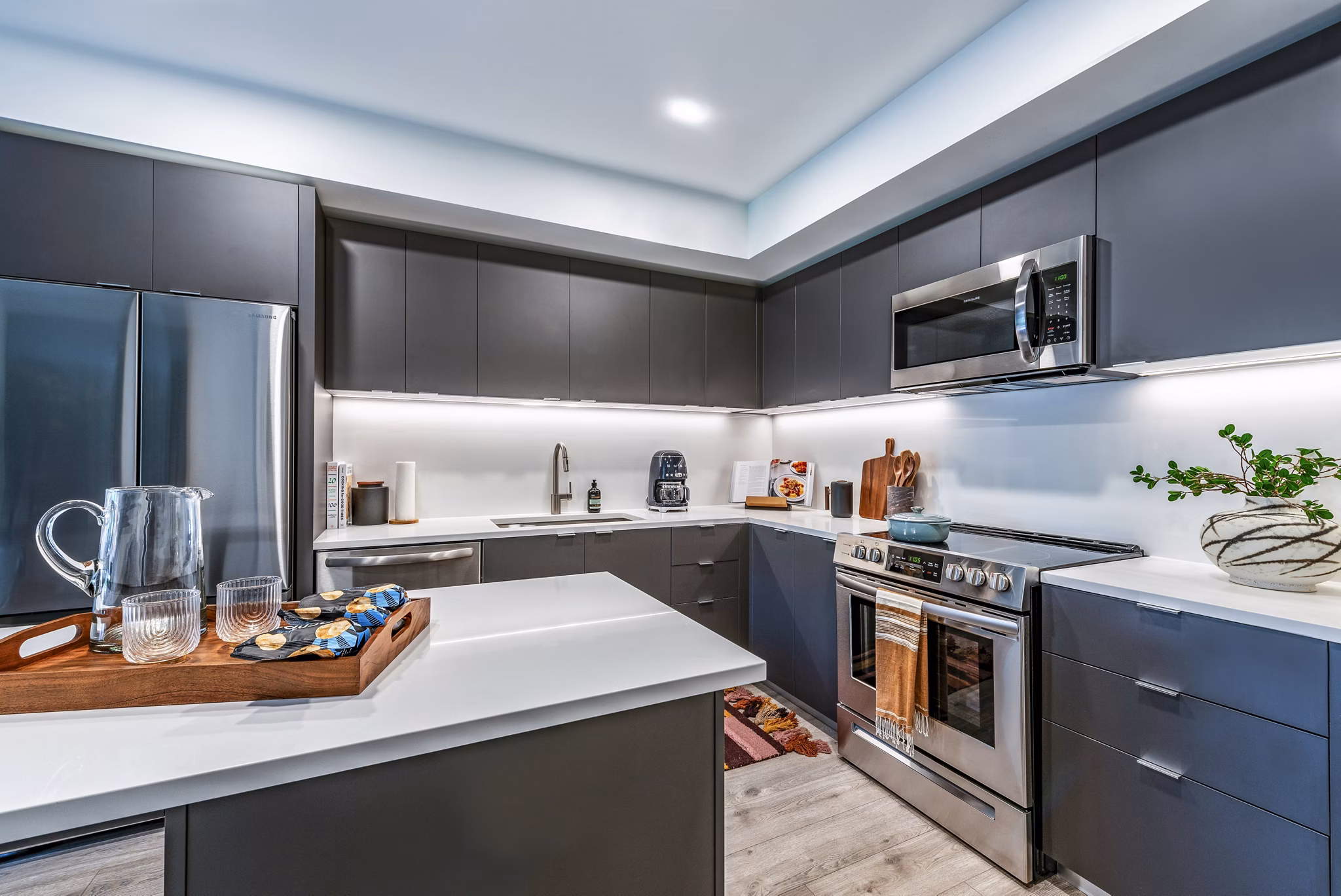 Modern kitchen featuring dark cabinets and stainless steel appliances with a white countertop in luxury apartments
