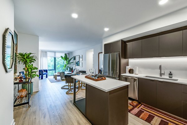 Modern kitchen and living area featuring a kitchen island and stainless steel appliances in luxury apartments