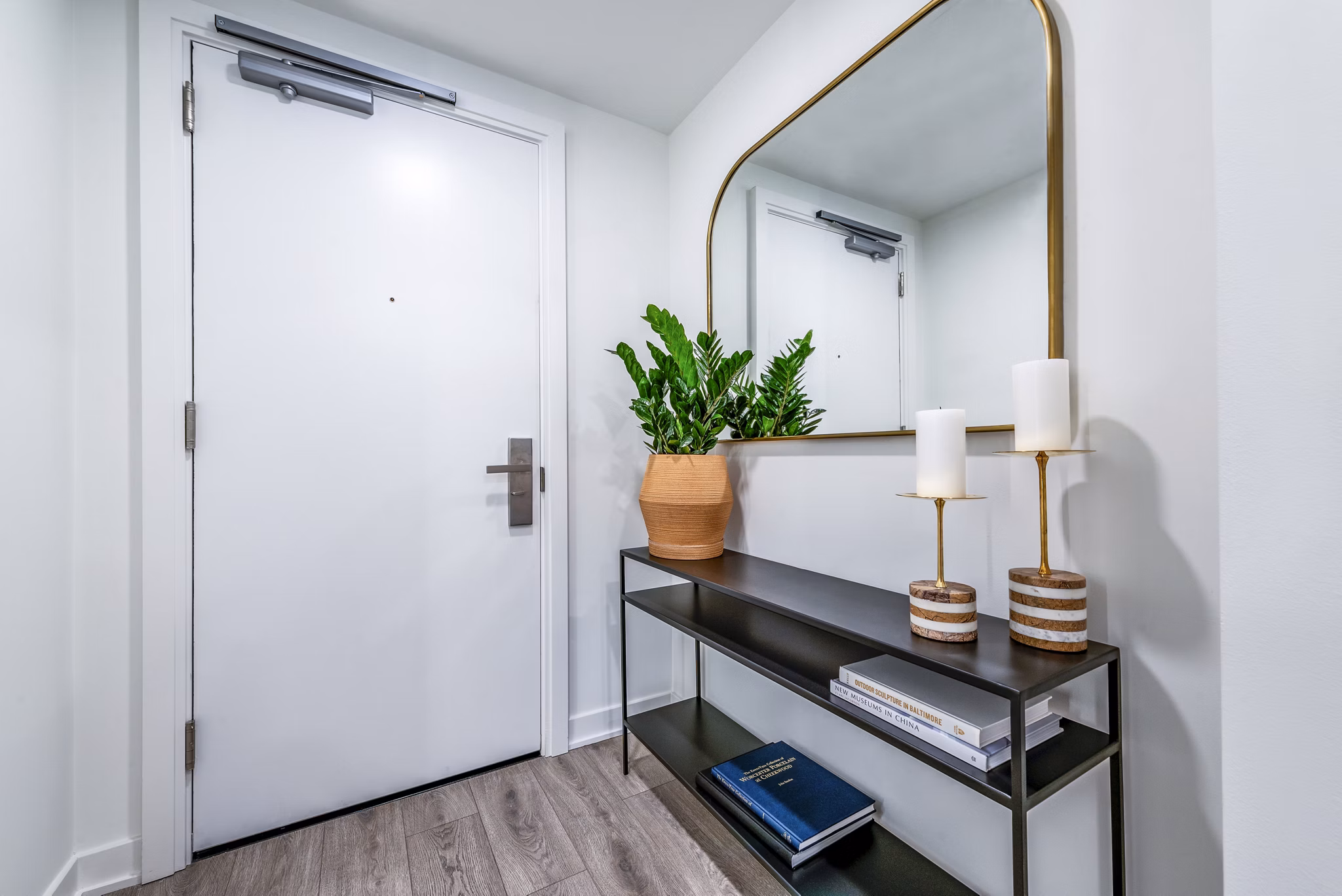 Modern entryway with white door, console table, and large mirror in luxury apartment