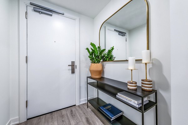 Modern entryway with white door, console table, and large mirror in luxury apartment