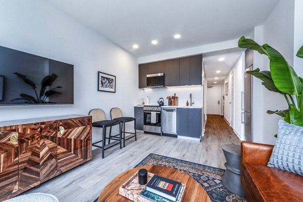 Modern living room and kitchen with a leather sofa and bar stools in luxury apartments