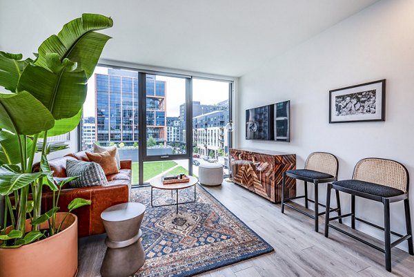 Modern living room with leather sofa, large plant, and city view in luxury apartment