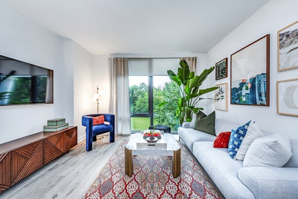 Modern living room with a sofa, blue armchair, and large windows in luxury apartment