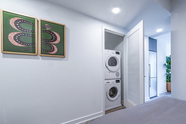Laundry room with stackable washer and dryer and snake-themed artwork at luxury apartments