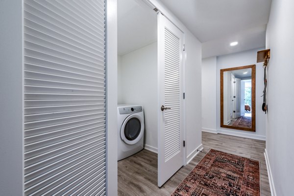 Hallway featuring a washing machine, large mirror, and decorative rug in luxury apartment