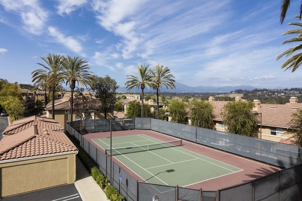 Outdoor tennis court surrounded by lush greenery at Barcelona Apartments, ideal for sports enthusiasts seeking fitness activities