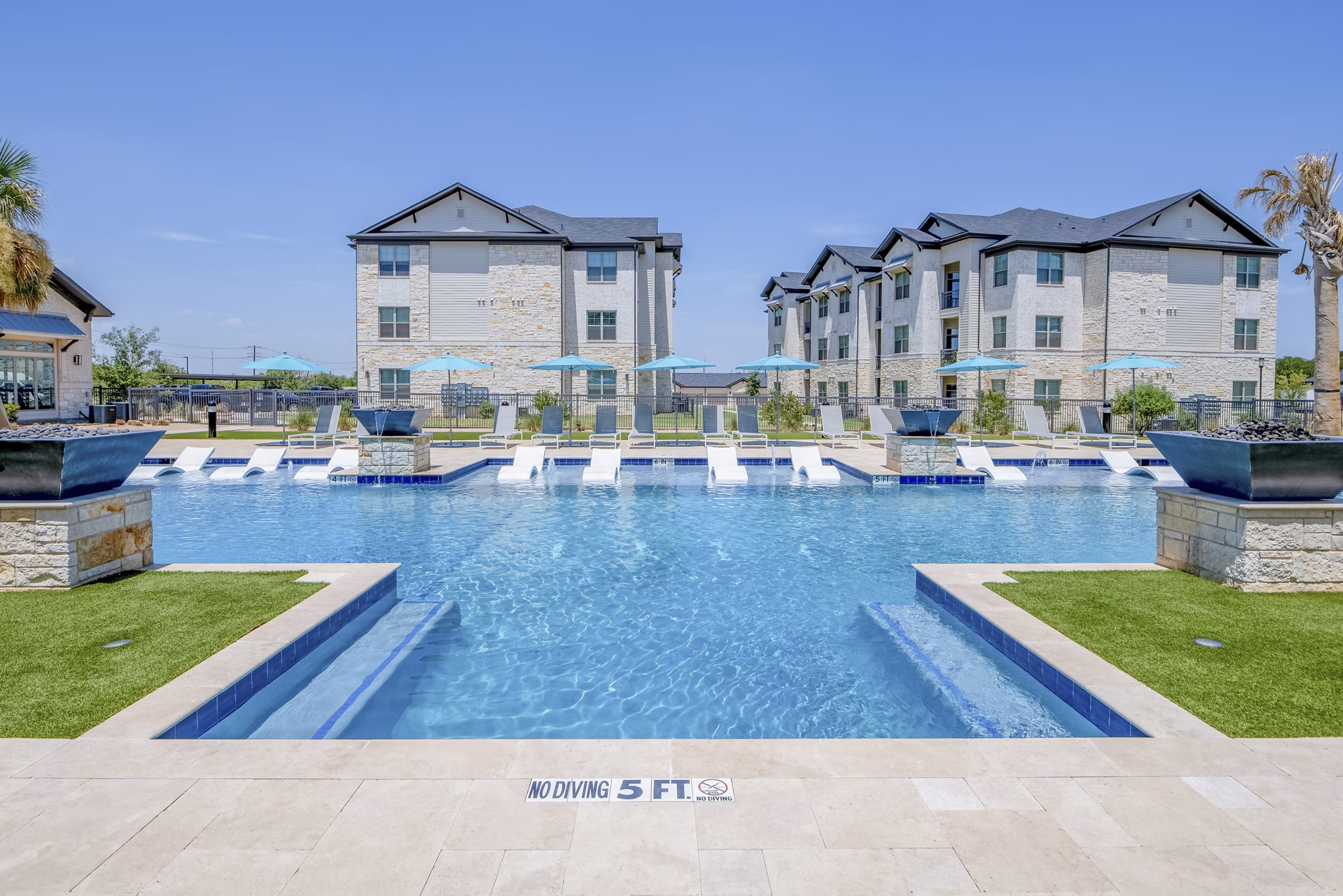 Resort-style swimming pool at The Mark at Denton Apartments with lounge chairs and landscaped surroundings