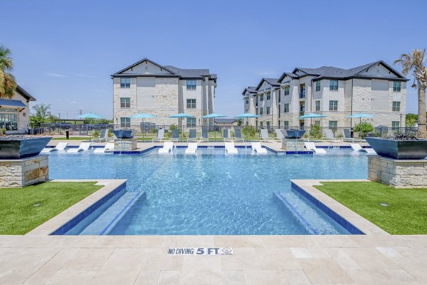 Resort-style swimming pool at The Mark at Denton Apartments with lounge chairs and landscaped surroundings