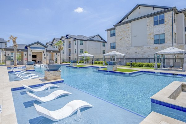 Resort-style pool with surrounding loungers at The Mark at Denton Apartments offering luxury living