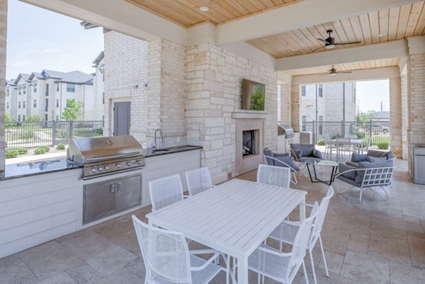 Grill area with seating at The Mark at Denton Apartments, ideal for outdoor gatherings and relaxation