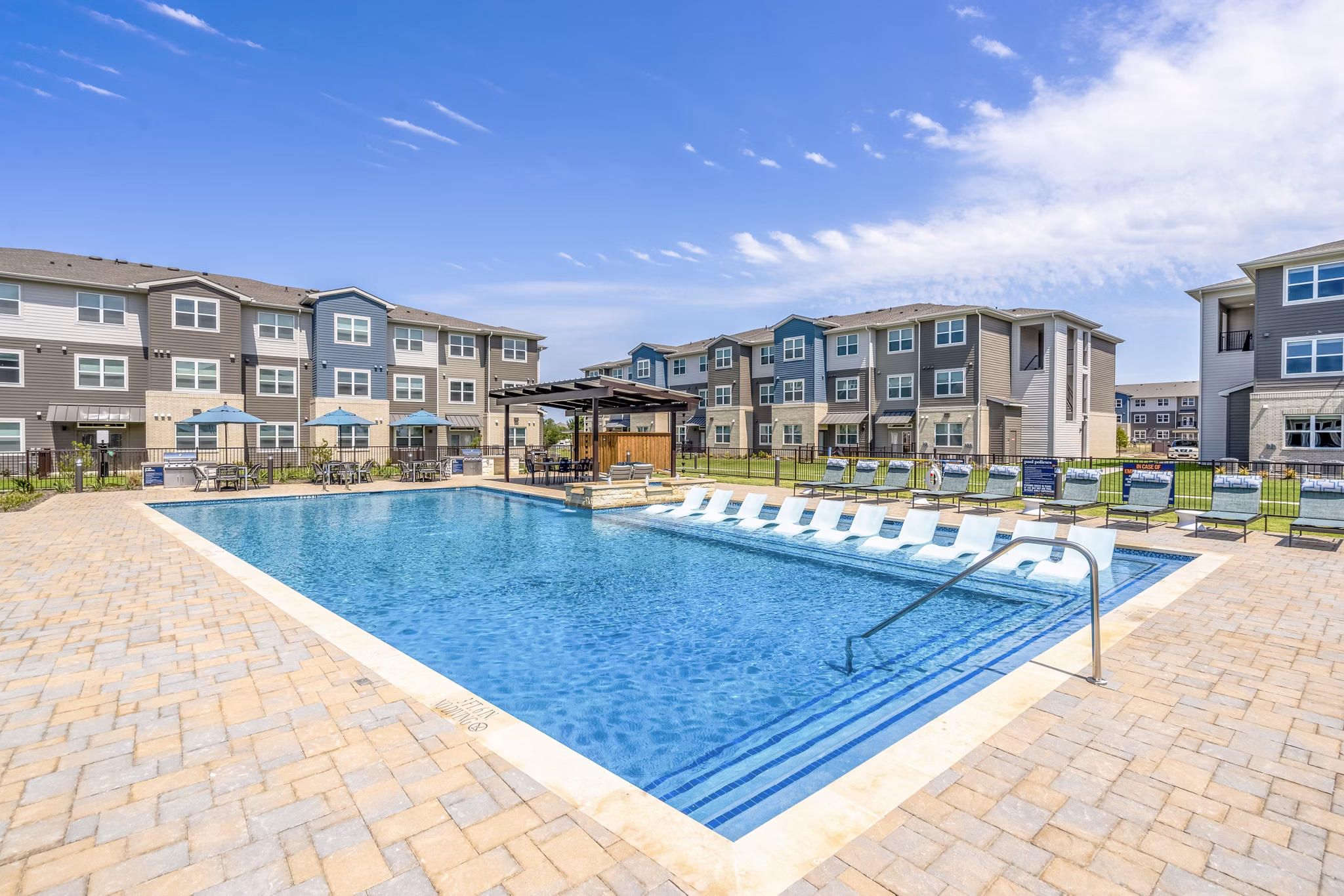Resort-style pool at Prose Northbend Apartments with lounge chairs and lush landscaping for ultimate relaxation