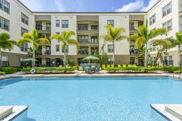 Relaxing poolside oasis at The Village at Lake Lily Apartments featuring lush landscaping and modern design