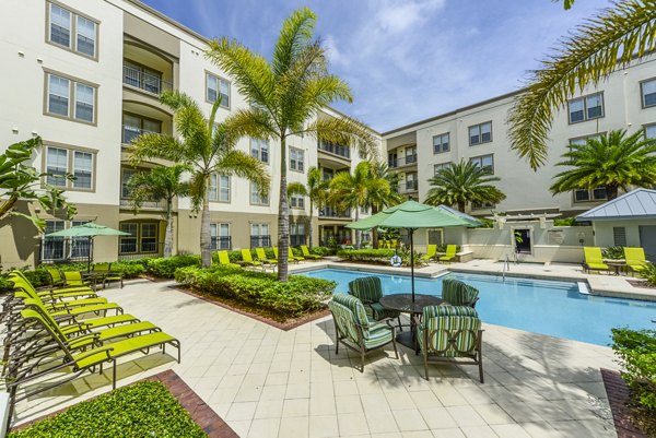Resort-style pool surrounded by lush landscaping at The Village at Lake Lily Apartments