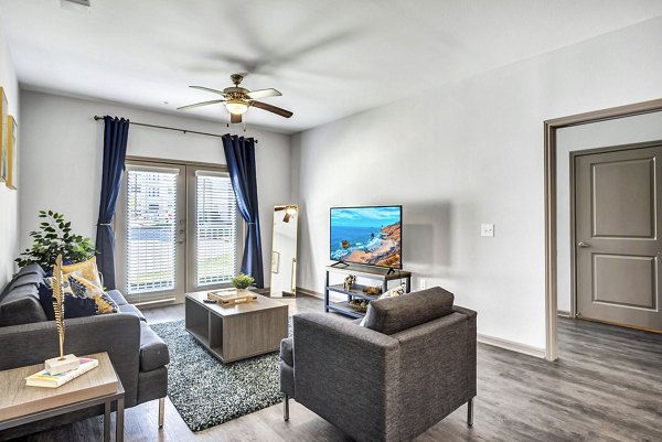 Cozy living room with modern decor in Haven at M Apartments featuring plush seating and large windows