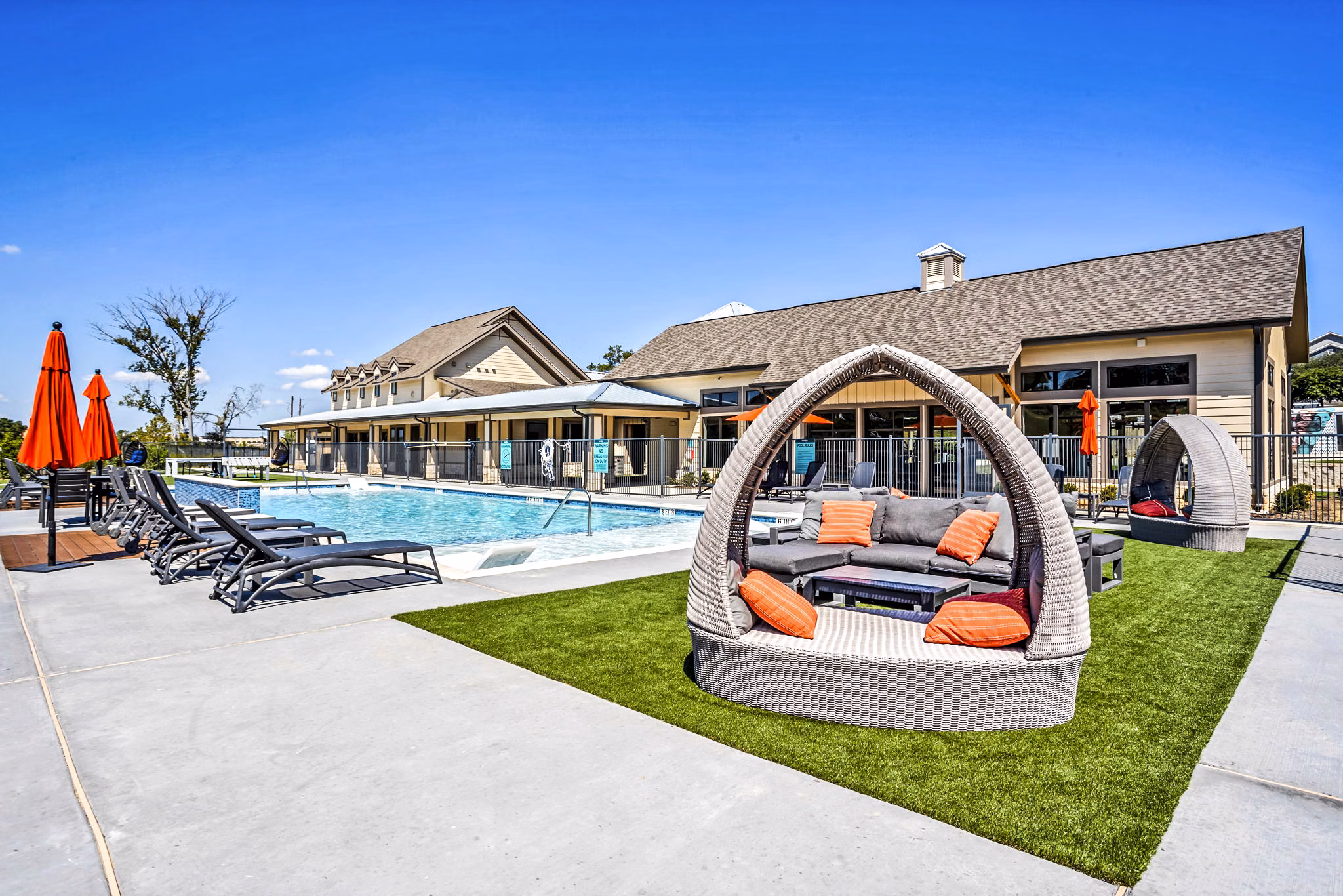 Outdoor pool patio at Haven at M Apartments offers luxury relaxation with sleek lounge chairs and vibrant greenery backdrop
