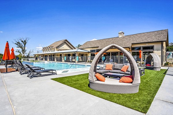 Outdoor pool patio at Haven at M Apartments offers luxury relaxation with sleek lounge chairs and vibrant greenery backdrop