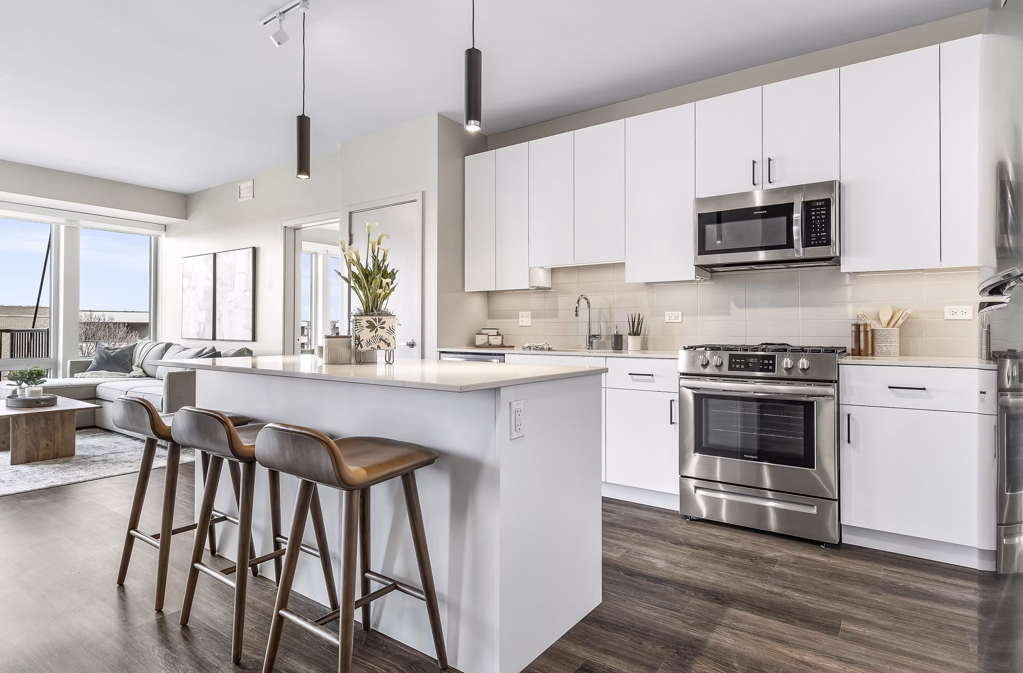 Modern living room with sleek furnishings and abundant natural light in District 1860 Apartments