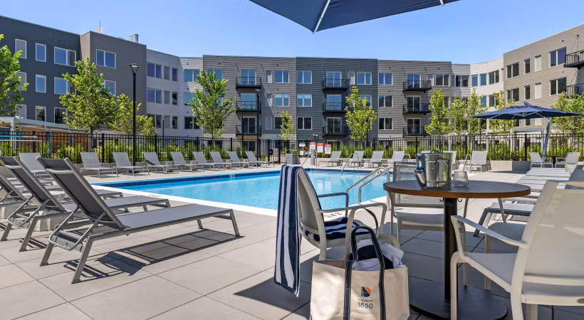 Outdoor pool with lounge chairs at District 1860 Apartments, modern luxury living space