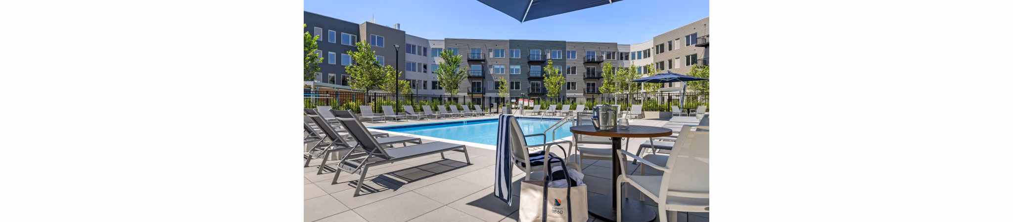 Outdoor pool with lounge chairs at District 1860 Apartments, modern luxury living space