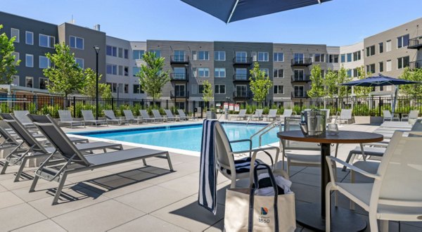 Outdoor pool with lounge chairs at District 1860 Apartments, modern luxury living space