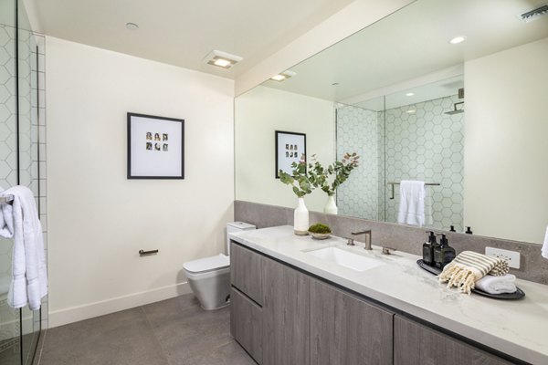 The Alfred Apartments: Modern bathroom featuring sleek cabinetry and large mirror