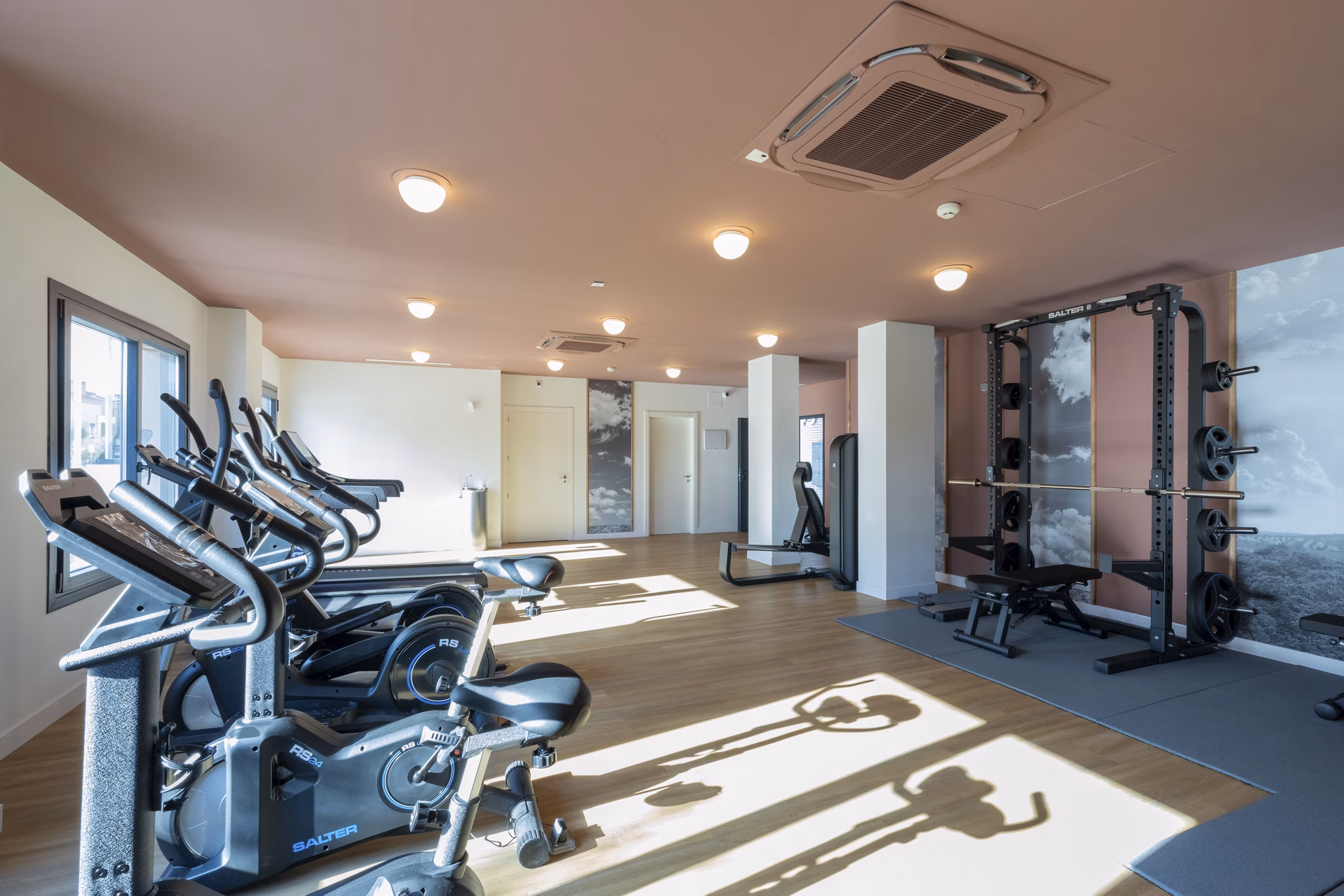 Spacious gym area with modern workout equipment and mirrored walls at Be Casa Essential Canaveral.
