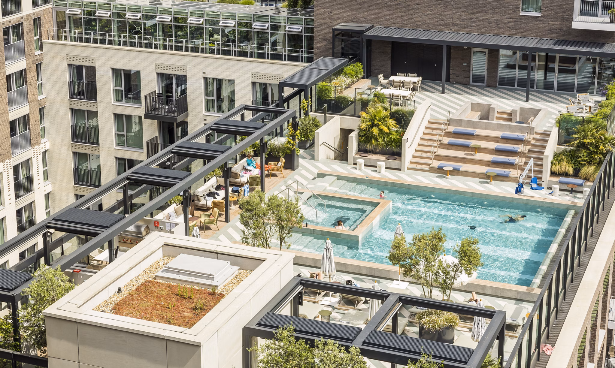 Rooftop pool and lounge area with modern design and lush landscaping at a luxury apartment building.