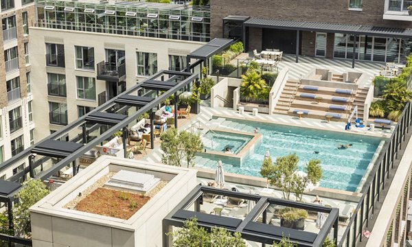 Rooftop pool and lounge area with modern design and lush landscaping at a luxury apartment building.