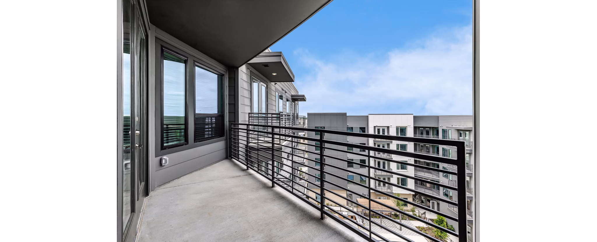 Spacious patio with stylish seating and greenery at Crosstown Apartments, perfect for relaxation and community gatherings