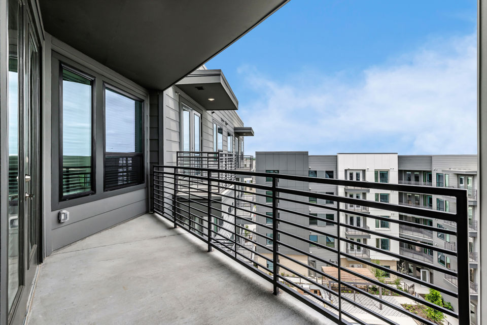 Spacious patio with stylish seating and greenery at Crosstown Apartments, perfect for relaxation and community gatherings