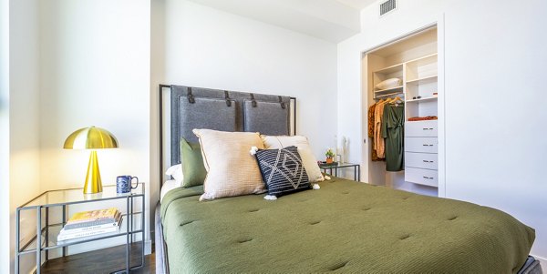 Modern bedroom featuring cozy furnishings and city views at Skye on 6th Apartments