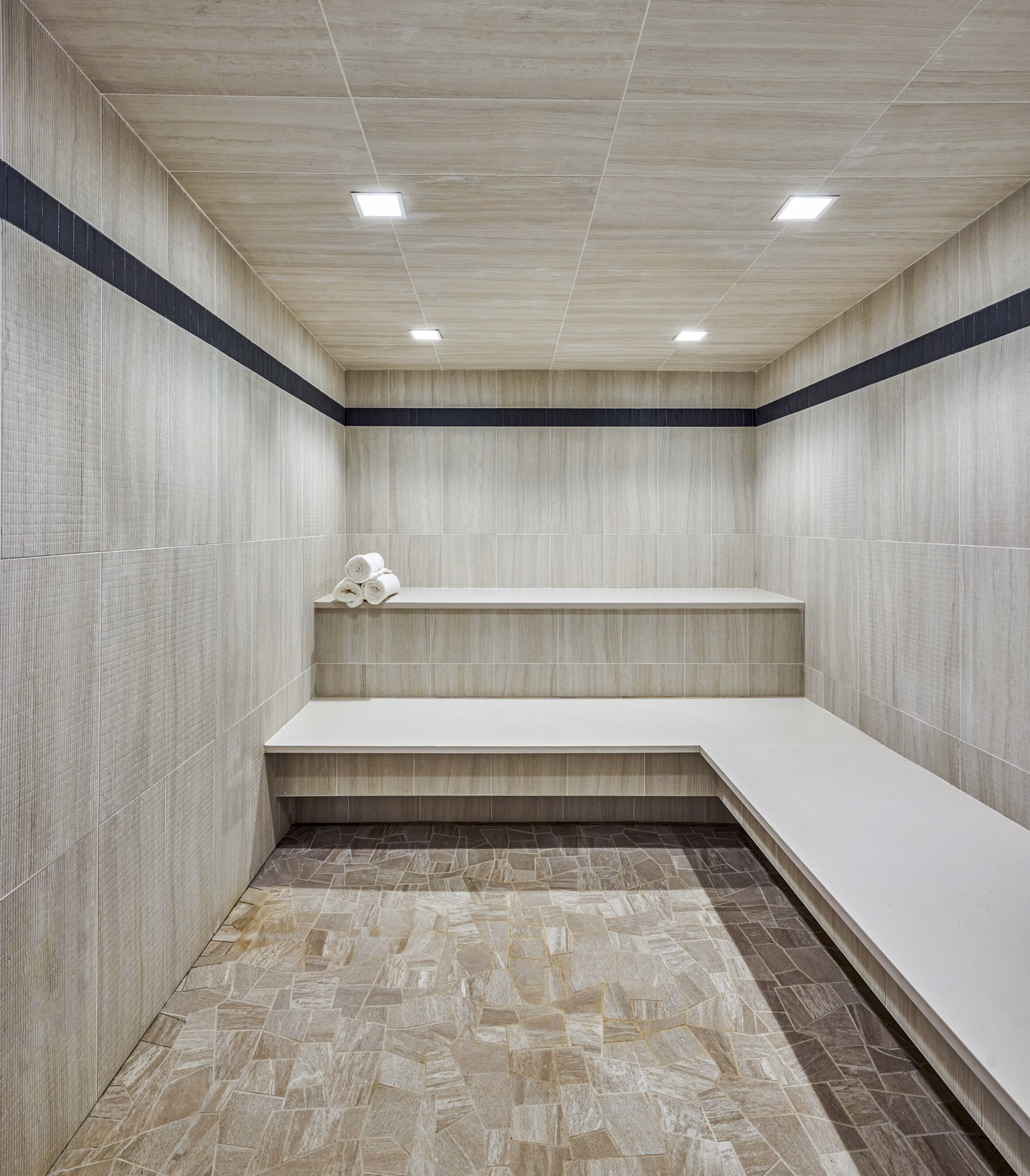 Sauna with wooden benches and ambient lighting at Skye on 6th Apartments, perfect for relaxation and wellness activities