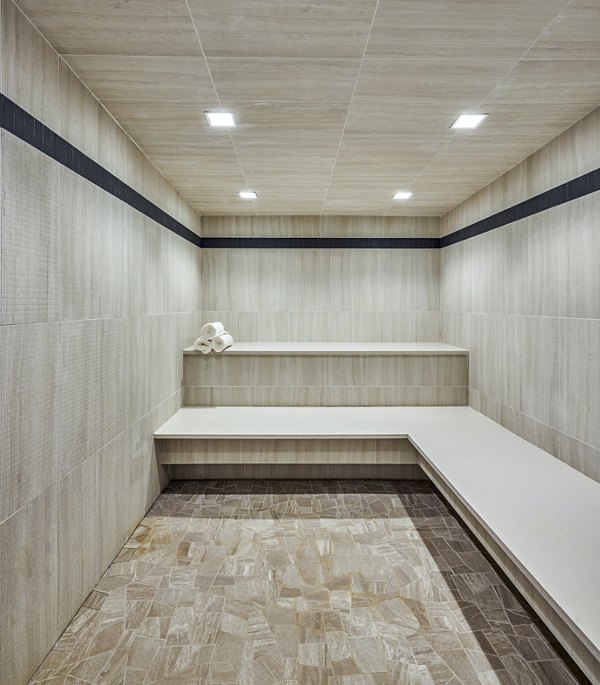 Sauna with wooden benches and ambient lighting at Skye on 6th Apartments, perfect for relaxation and wellness activities