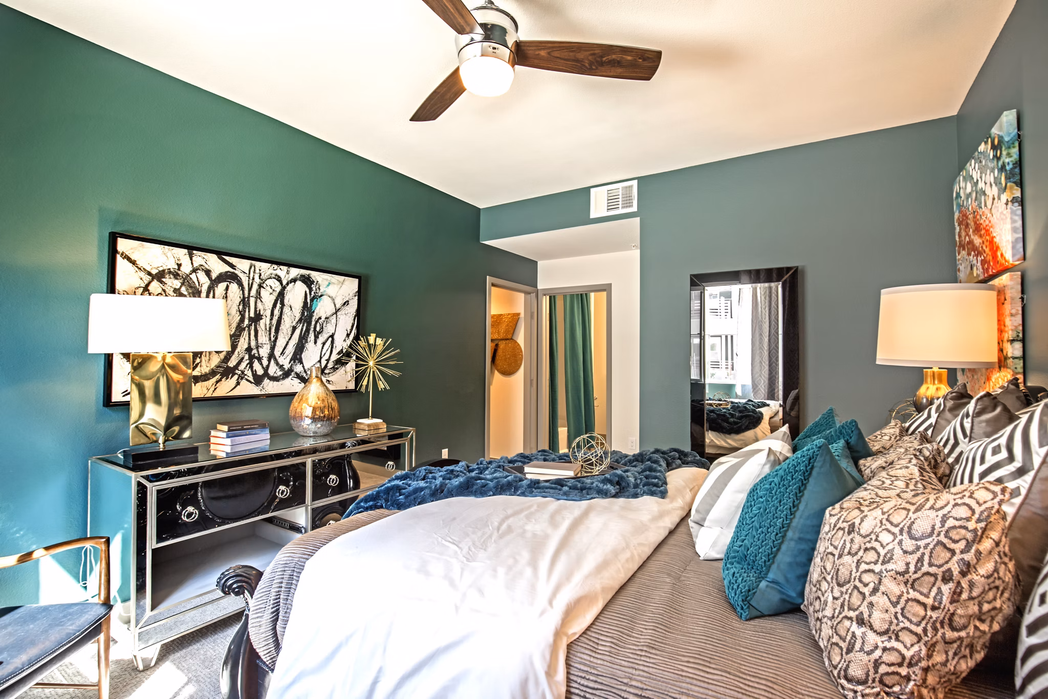 Cozy bedroom with modern decor at Constellation Apartments, featuring plush bedding and large windows in a luxury setting