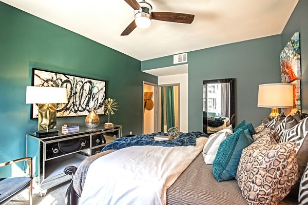 Cozy bedroom with modern decor at Constellation Apartments, featuring plush bedding and large windows in a luxury setting