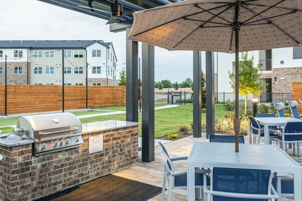 Outdoor grill area and patio with seating at Prose District West Apartments, a luxury Greystar community